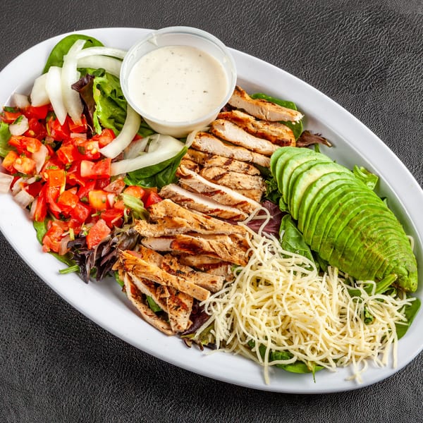 A Dona Mary Mexican grilled chicken salad with avocado, pico de gallo, onions, cheese, and dressing.