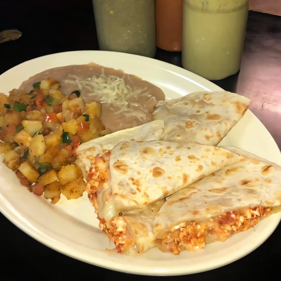 Dona Mary's Mexican plate with quesadillas, refried beans, and diced potatoes, with salsa bottles in the background.