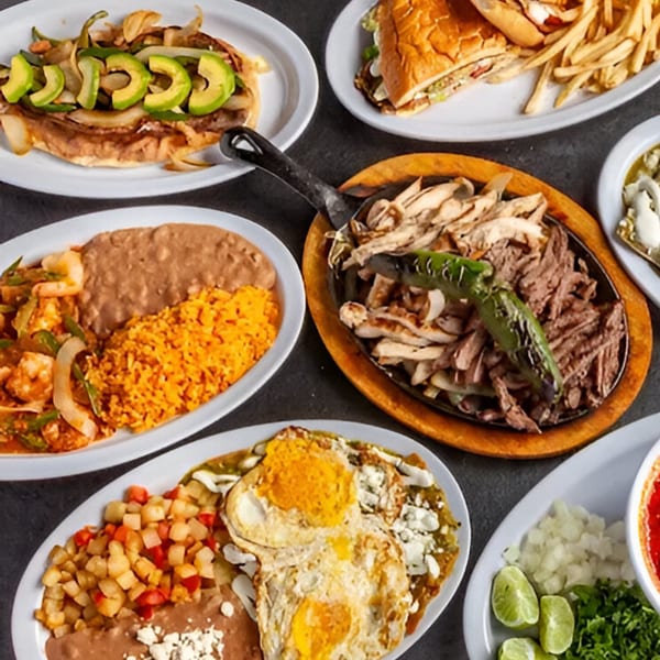 A top-down view of various Mexican dishes, including fajitas, a torta, and breakfast plates.