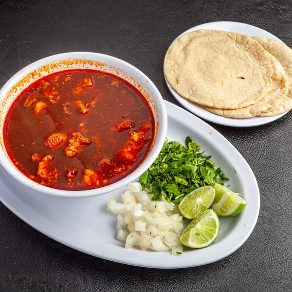 Dona Mary's menudo, a rich red soup with tripe, served with tortillas, cilantro, onions, and lime.
