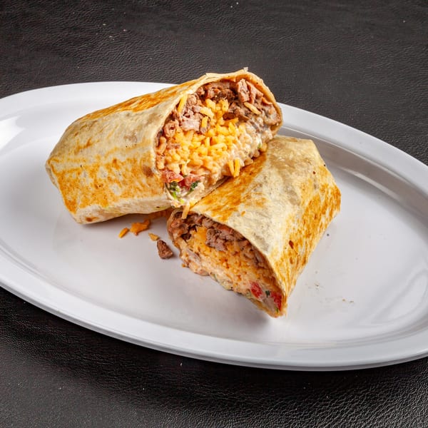 A Dona Mary burrito, cut in half, revealing rice, meat, and cheese on a white plate.