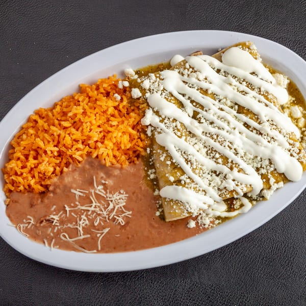Dona Mary's enchiladas with green sauce, sour cream, and cheese, served with rice and refried beans.